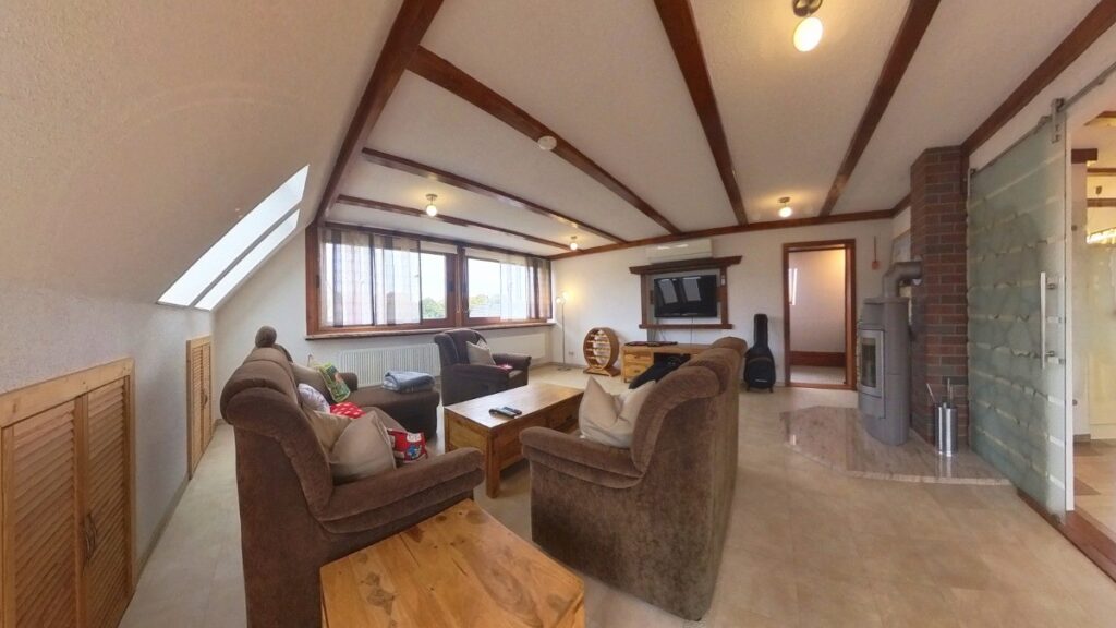 Wohnzimmer mit Kaminofen, Panoramafenstern und Balkonzugang