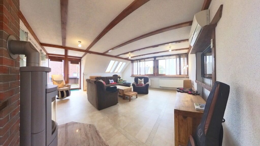 Wohnzimmer mit Kaminofen, Panoramafenstern und Balkonzugang