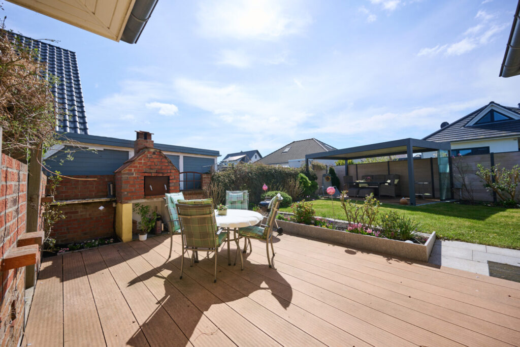 Sonnige Südterrasse am Haus mit überdachtem Freisitz im Hintergrund