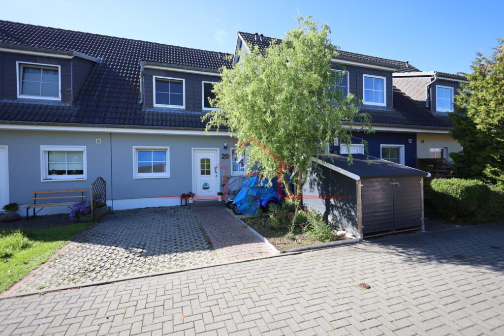 Blick von der Privatstraße auf das Wohnhaus mit Vorgarten und Stellplatz