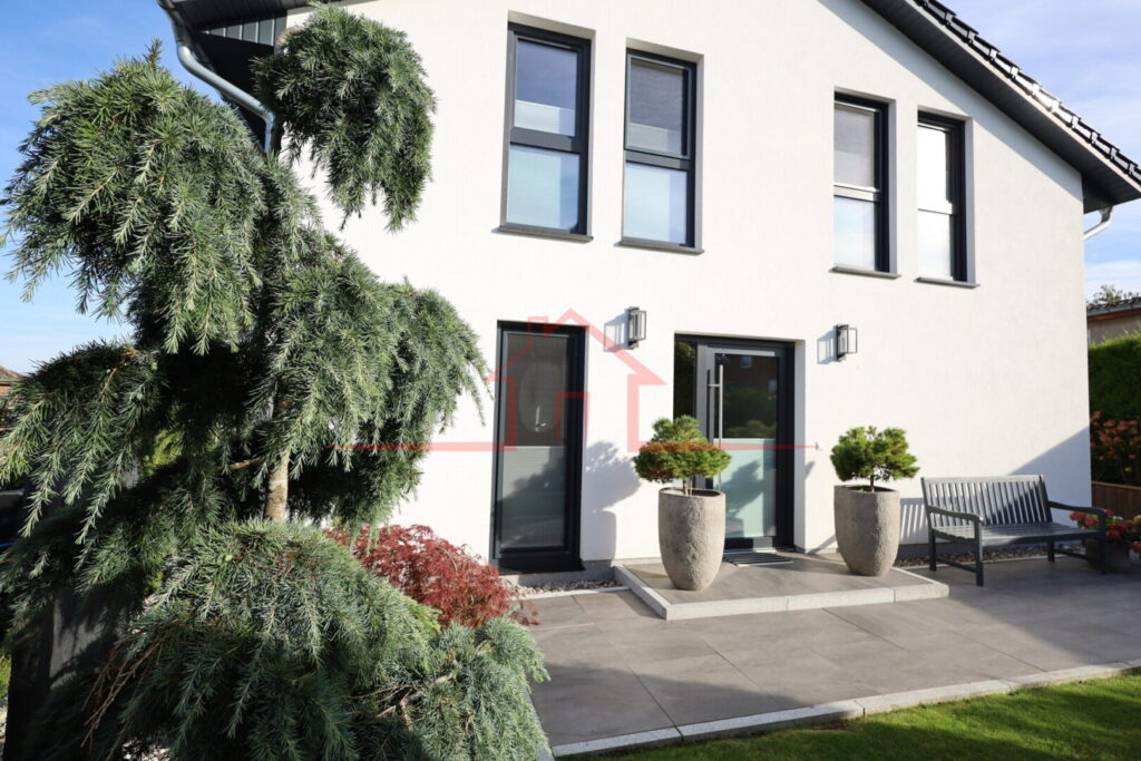 Gepflegte Hausseite mit sonniger Terrasse und liebevoll gestalteter Gartenanlage