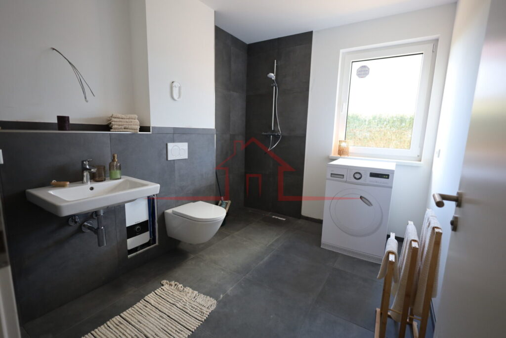 Modernes Badezimmer mit bodengleicher Dusche und zeitgemäßer Ausstattung